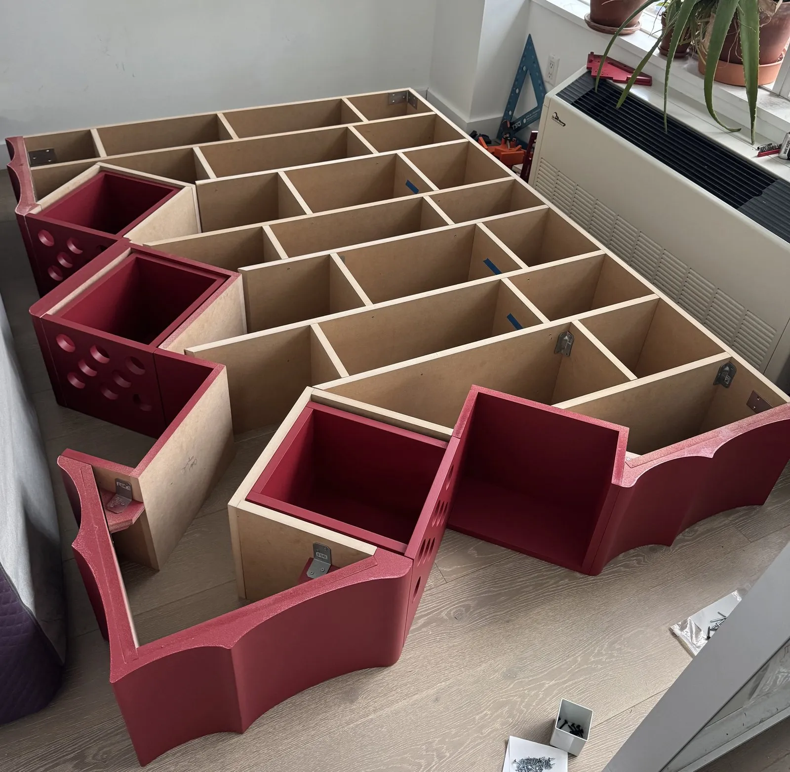 A cellular plywood piece with red curved panels being assembled on the floor