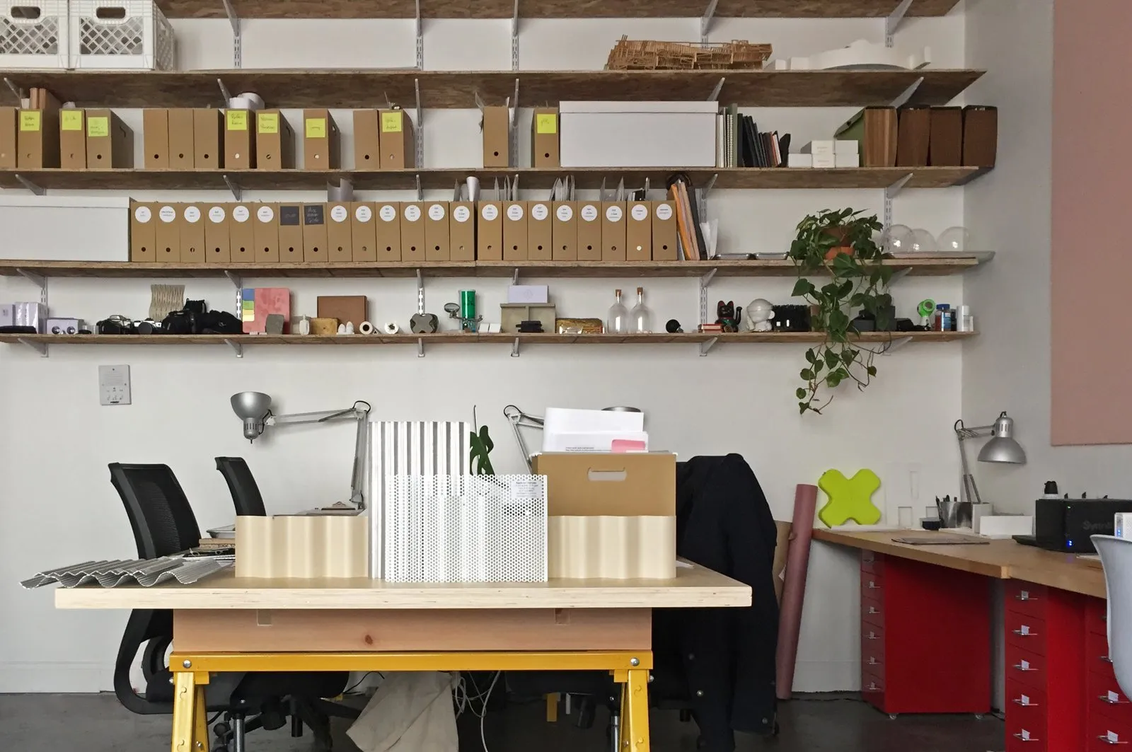 The SOAP studio: a long worktable with lamps and samples, shelves of boxed archives and models above